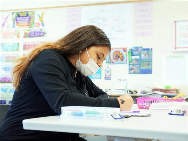 Tymberlynn Deaver writing on paper in classroom