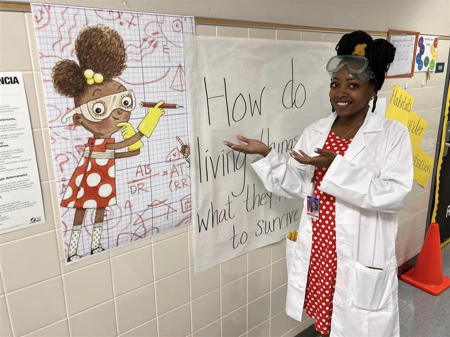 Teacher smiling and pointing at wall