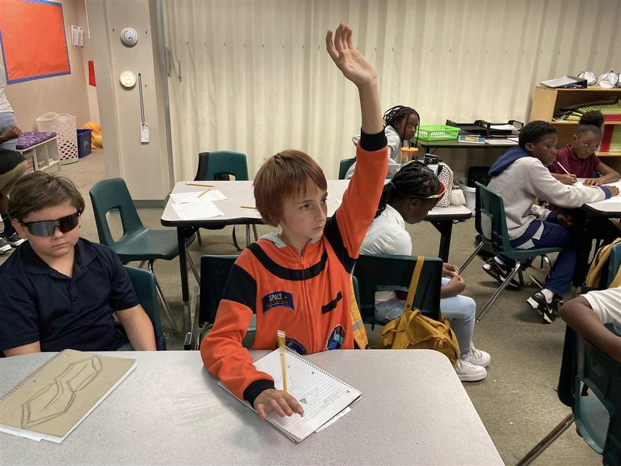 Student raising hand in classroom